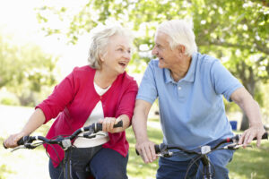 A senior couple laughing and smiling while riding bikes together