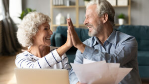 Senior couple share high five for learning how to afford assisted living in Elkhorn