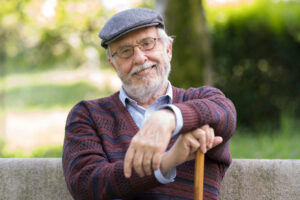 A happy senior man smiles while sitting on a park bench