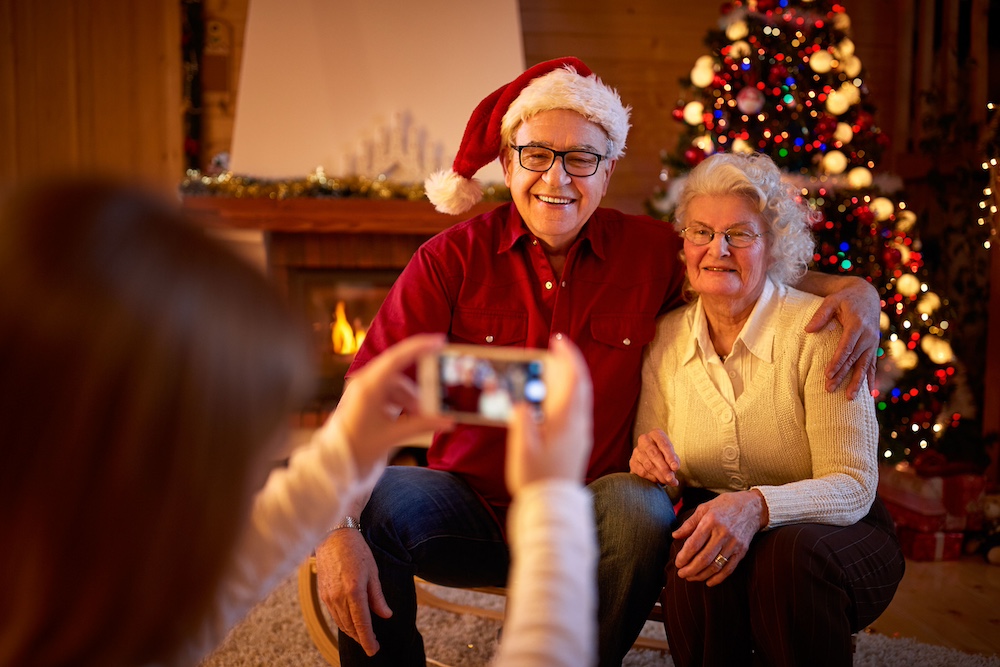 A woman taking a photo of her senior parents during the holidays