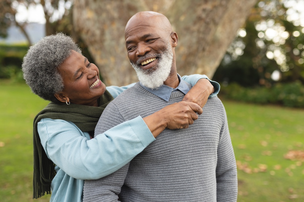 A happy senior couple shares a hug together outdoors